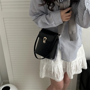 Sac seau chic en cuir noir mat avec boucle fer à cheval dorée et longue bandoulière
