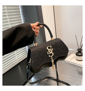 Detail of black sequined crossbody bag with golden S logo and elegant long fringe tassel