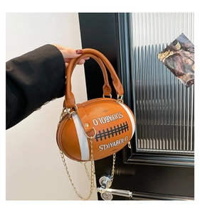 Macro shot of brown leather football shaped bag with golden chain and SDIYABOLO logo
