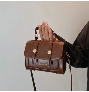 Detail of dark brown faux leather handbag with oily wax finish and gold fashion logo