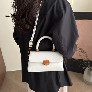 Minimalist white leather crossbody bag with top handle and gold metal lock detail