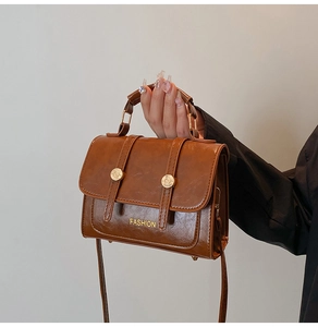 Detail view of the brown vintage crossbody bag with metal rings and fashion branding