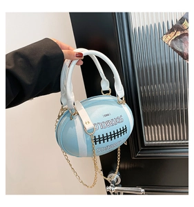 Macro shot of blue rugby-shaped crossbody bag with white handles and gold chain strap