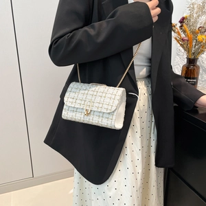 Elegant plaid tweed crossbody bag with gold chain strap shown on a model in a minimal setting