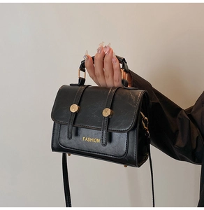 Close-up of black PU leather handbag with gold FASHION text and metal buckle details