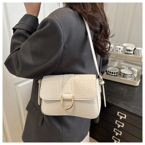 Detail of white woven texture shoulder bag with gold horseshoe buckle on grey blazer