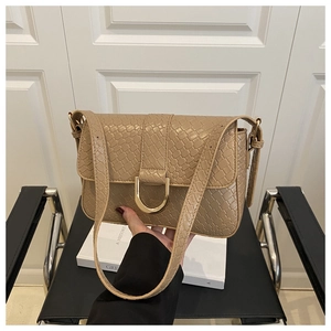 Detailed close-up of khaki crocodile pattern handbag featuring a gold D-buckle ornament