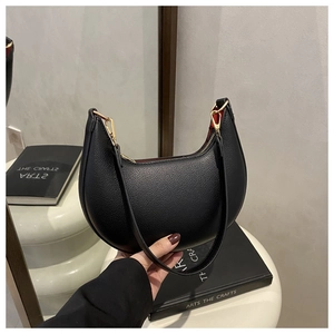 Detail of minimalist black pebbled leather crescent bag with vibrant red interior lining
