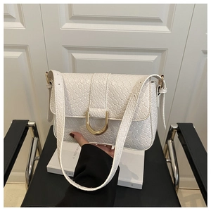 Close-up of white woven textured handbag featuring a gold horseshoe buckle detail