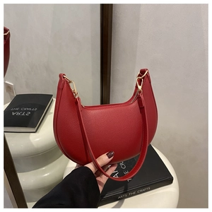 Detailed macro view of the red lychee-patterned leather surface and golden zipper of this hobo bag