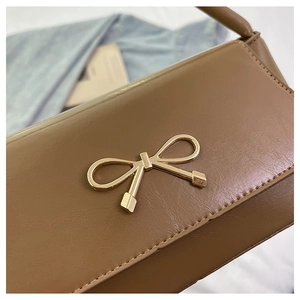 Gros plan du fermoir nœud en métal doré sur le sac à bandoulière marron vintage