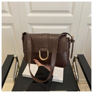 Close-up of woven texture dark coffee leather handbag with gold horse-shoe metal buckle
