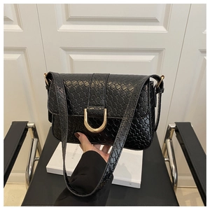 Detail of black woven shoulder bag with gold D-ring buckle and crocodile texture
