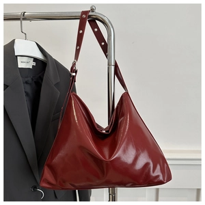 Detail of vintage burgundy tote bag showing glossy leather texture and metal buckle