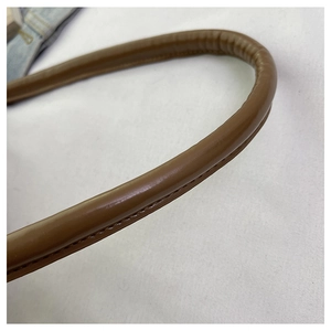 Détail macro de l'anse de sac à main en cuir marron avec surpiqûres et texture lisse
