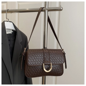 Detail of dark brown woven shoulder bag with a gold horseshoe buckle on the flap cover