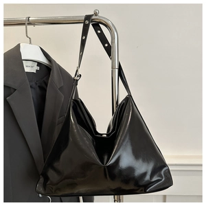 Detail of glossy black oil wax leather hobo bag featuring silver eyelet strap buckles