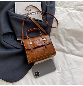 Detailed view of caramel messenger bag with star patches and adjustable strap on a blazer