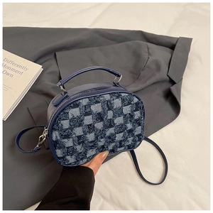 Detail of blue denim checkerboard handbag with frayed edges and silver hardware accents