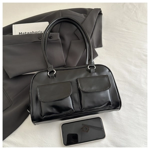 Detail view of glossy black leather tote with dual front pockets and silver ring hardware