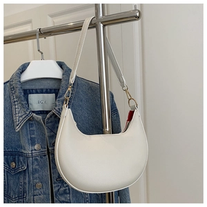 Detail of cream crescent shoulder bag with litchi texture and red fabric lining