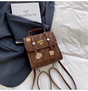 Close-up of vintage brown embroidered mini backpack with pleated texture and dual strap buckle