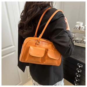 Bright orange PU leather shoulder bag with flap pockets worn by a model in a black suit
