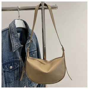 Detail view of khaki half-moon leather bag on hanger with denim jacket styling