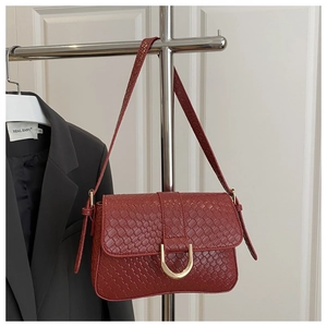 Detail of burgundy woven leather handbag with gold horseshoe buckle on silver hanger