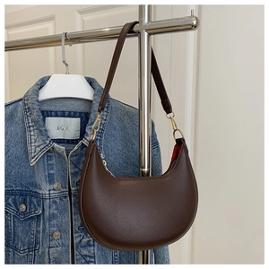 Detail of dark brown lychee leather crescent bag with golden metal hardware and strap