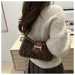 Détail du sac léopard avec boucle dorée porté par un mannequin dans un intérieur