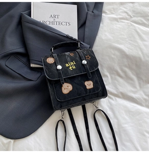 Close-up of black pleated mini backpack featuring cartoon bear and star embroidery details
