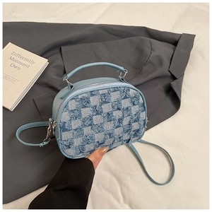 Close-up of light blue denim plaid crossbody bag with frayed edges and PU strap held by hand