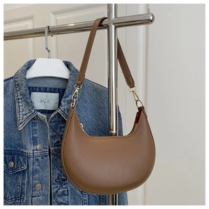 Close-up of brown crescent underarm bag with lychee leather texture and gold hardware