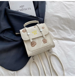 Detail view of cream vintage college backpack with star embroidery on navy blazer background