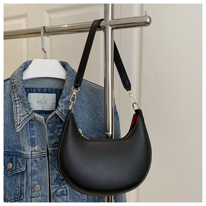 Detail of black crescent bag with lychee pattern leather and gold metal zipper hardware