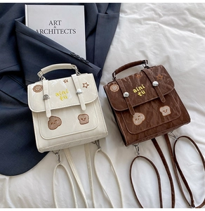 Detailed view of cream and brown embroidered mini backpacks with vintage texture and buckles