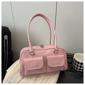 Detailed view of a pink gloss shoulder bag with double front pockets on a table