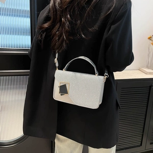 Silberne Pailletten-Umhängetasche mit goldener Schnalle über einem schwarzen Blazer