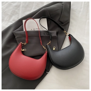 Detail of red and black crescent shoulder bags with lychee grain texture and gold zippers