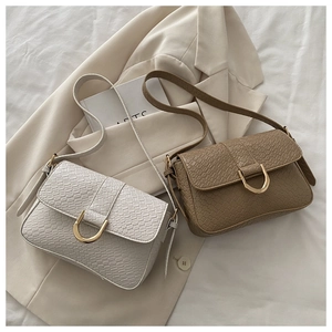 Detail of crocodile embossed leather bags with golden D-ring buckles on beige blazer