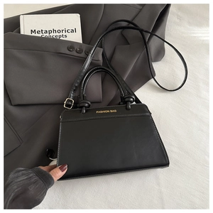 Detailed close-up of black matte leather tote bag with gold ring knot handle and logo