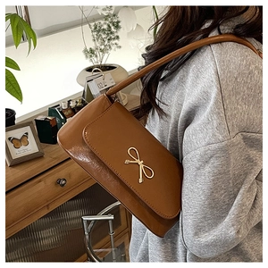Détail d'un sac à bandoulière en similicuir marron caramel avec boucle noeud dorée