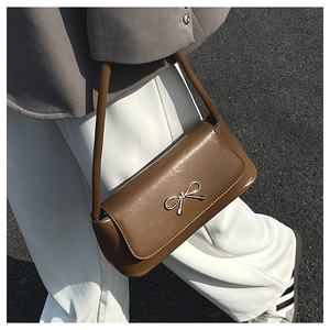 Vue détaillée du sac baguette en cuir verni marron avec un fermoir nœud doré