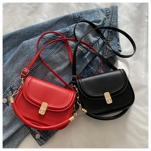 Detail of red and black saddle bags with gold metal clasps on a denim jacket background