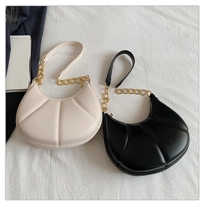 Detail of solid color crescent shoulder bags with pleated texture and gold chain straps