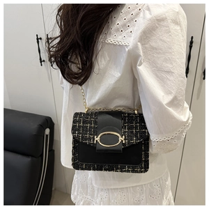 Close-up of black tweed and leather handbag with gold metal clasp and chain strap