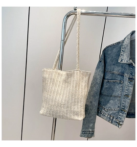 Close-up of beige woven tote bag with vertical texture detail and long shoulder handle
