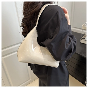 Close-up of glossy cream patent leather hobo bag with embossed logo on shoulder strap