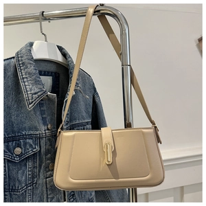 Detail of minimalist beige baguette bag showing its sleek metal buckle and PU leather texture